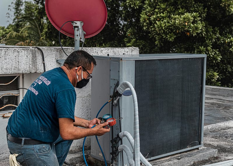 a man wearing a face mask working on a roof top unit