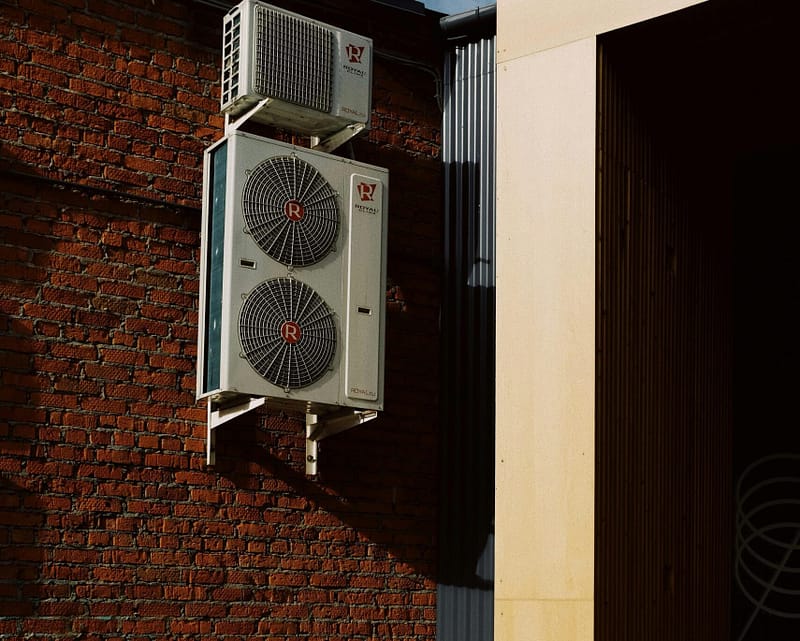 a two white air conditioning units on a brick wall